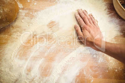 Hand of baker rubbing flour on the table