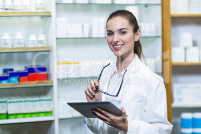 Smiling pharmacist holding digital tablet in pharmacy