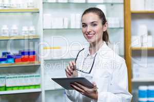 Smiling pharmacist holding digital tablet in pharmacy
