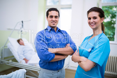 Smiling doctor and nurse standing with arms crossed