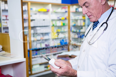 Pharmacist holding digital tablet while checking medicine