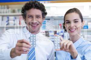 Smiling pharmacist showing medicine in pharmacy