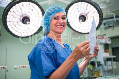 Portrait of smiling surgeon holding report in operation room