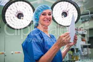 Portrait of smiling surgeon holding report in operation room