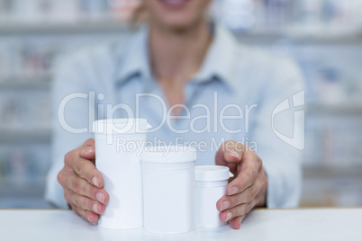 Pharmacist holding medicine container in pharmacy