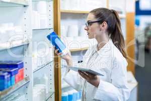 Pharmacist holding digital tablet while checking medicine