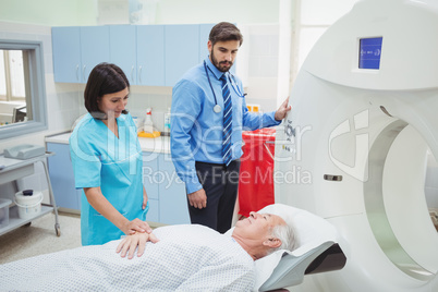 A patient is loaded into an mri machine while doctor and technic
