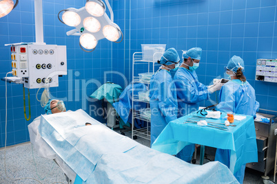Surgeons using digital tablet and patient lying on operation bed