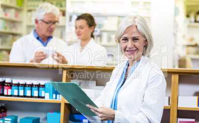 Pharmacist writing on clipboard in pharmacy