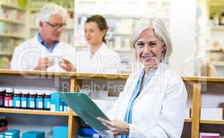 Pharmacist writing on clipboard in pharmacy