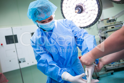 Nurse helping a surgeon in wearing surgical gloves