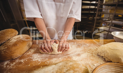 Mid-section of female baker kneading a dough