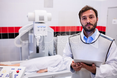 Doctor holding digital tablet and patient lying on x ray machine