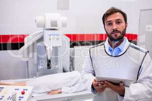 Doctor holding digital tablet and patient lying on x ray machine