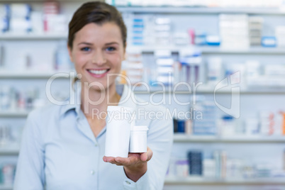 Smiling pharmacist showing medicine container in pharmacy