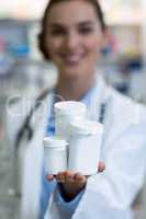 Pharmacist showing medicine container in pharmacy