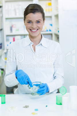 Smiling pharmacist grinding medicine in mortal and pestle at pha