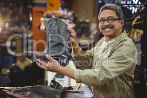 Portrait of smiling shoemaker holding a leather boot