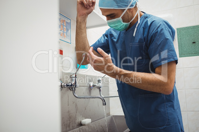 Male surgeon washing hands prior to operation using correct tech