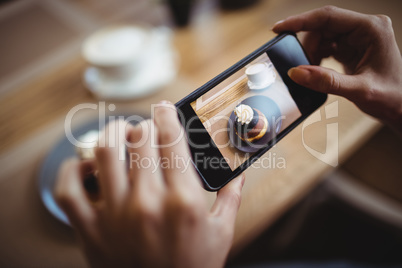 Hands of woman taking a photo of sweet food from mobile phone