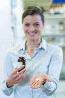 Pharmacist showing a medicine bottle and pills in pharmacy