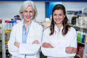 Smiling pharmacists standing with arms crossed in pharmacy