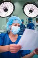 Female surgeon reading report in operation room