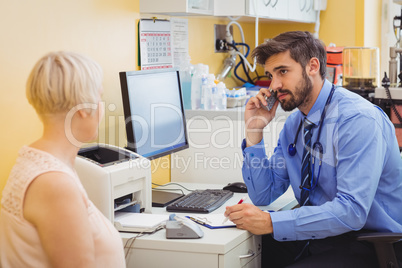 Doctor sitting at his desk and talking on phone