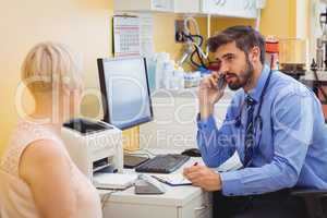 Doctor sitting at his desk and talking on phone