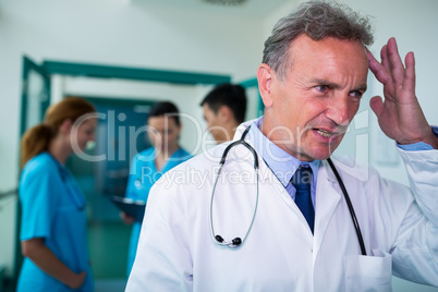 Tensed doctor standing in corridor