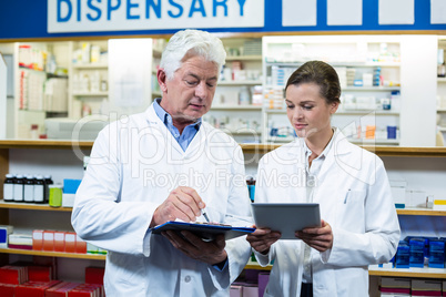 Pharmacists discussing on digital tablet and clipboard