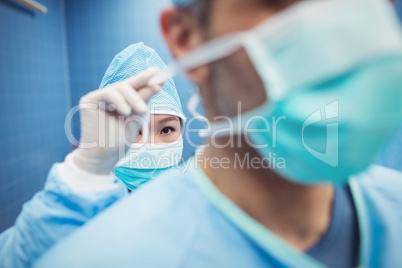 Nurse helping a surgeon in tying surgical mask