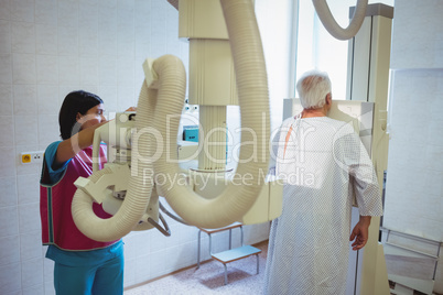 Female doctor sets up the machine to x-ray a patients spine