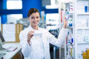 Pharmacist checking medicine in shelf at pharmacy