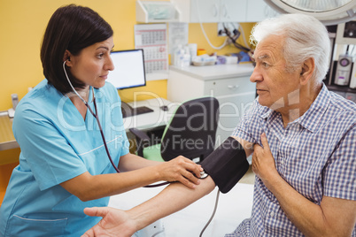 Female doctor checking blood pressure of patient