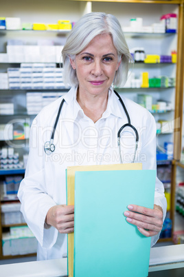 Pharmacist holding files in pharmacy