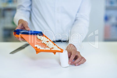 Pharmacist putting pill in container at pharmacy
