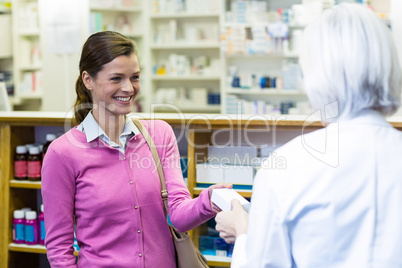 Pharmacist giving medicine box to customer
