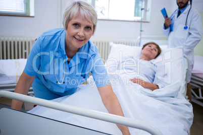 Smiling nurse spreading a blanket over patient