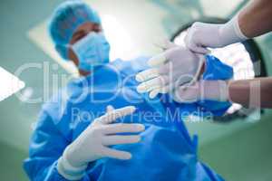 Nurse helping a surgeon in wearing surgical gloves