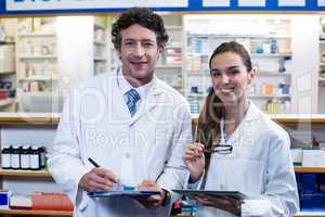Smiling pharmacists with clipboard and digital tablet in pharmac