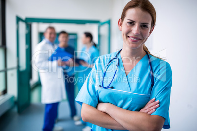 Portrait of smiling surgeon standing with arms crossed in corrid