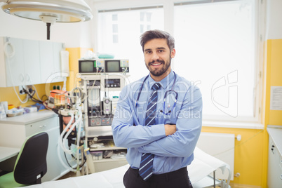 Portrait of smiling doctor standing with arms crossed