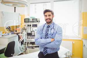 Portrait of smiling doctor standing with arms crossed