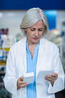 Pharmacist holding medicine while checking prescription