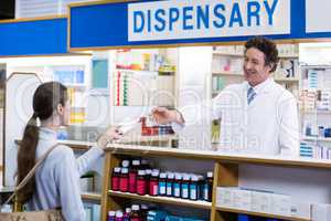 Pharmacist giving medicine box to customer