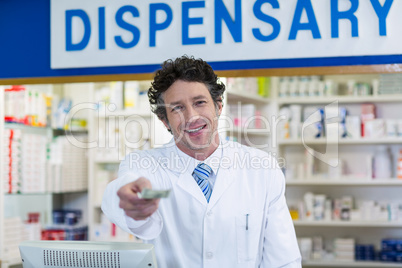 Pharmacist giving money to customer in pharmacy
