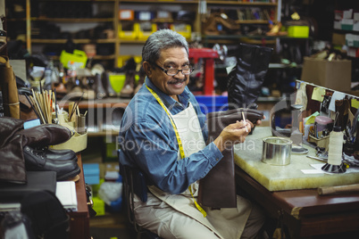 Portrait of smiling shoemaker applying glue on shoe