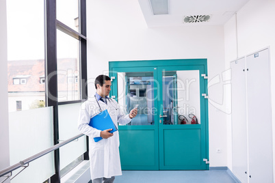 Doctor using mobile phone in corridor