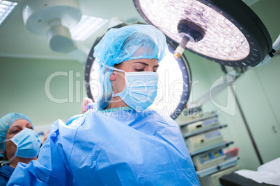 Nurse helping a surgeon in wearing scrub